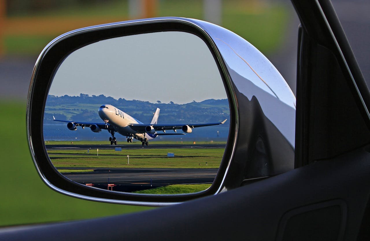 journey A jet airplane taking off is reflected in a car's side mirror, capturing a unique aviation perspective.
