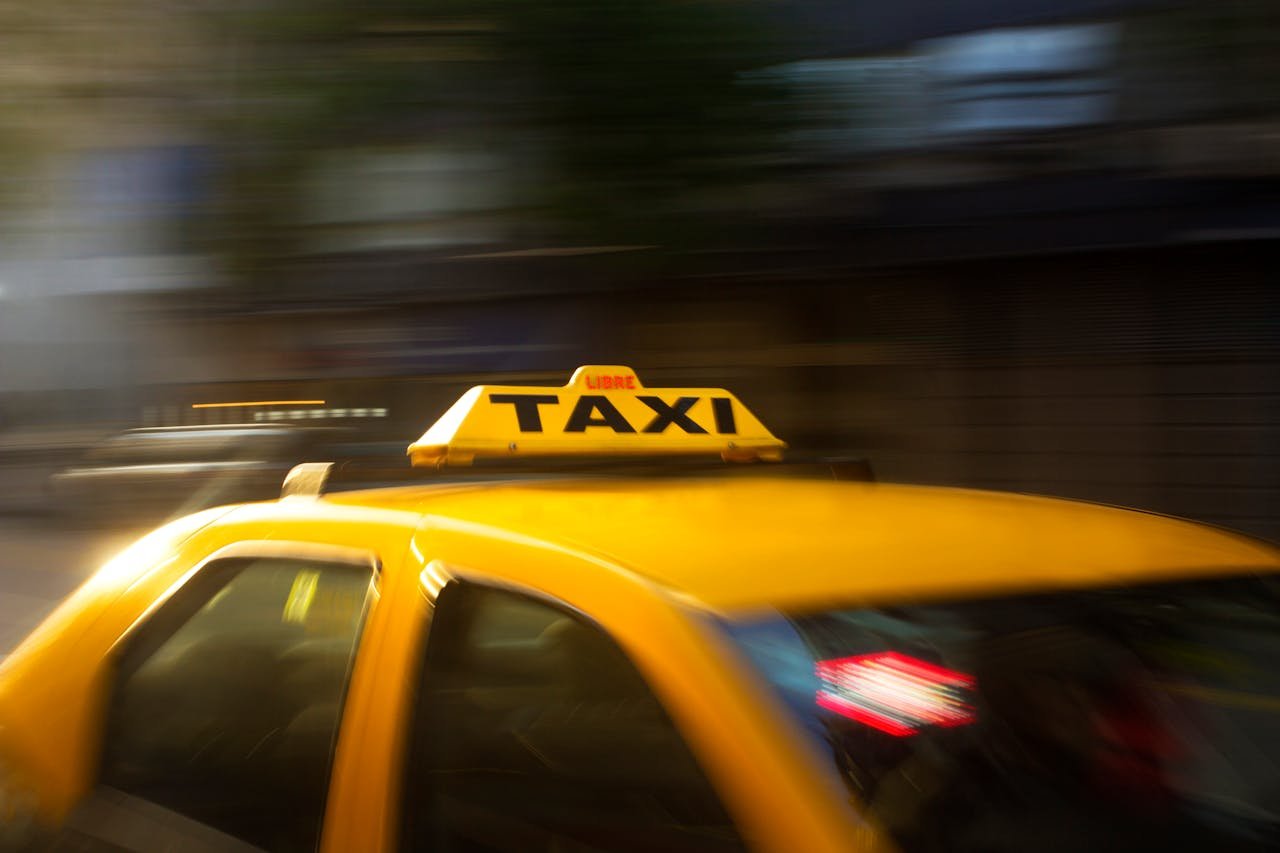 who-we-are A vibrant yellow taxi with motion blur speeding through a nighttime city street.