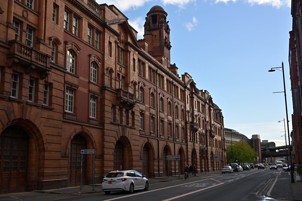 services-01 View of a historic red brick building on a street in Manchester on a clear day.